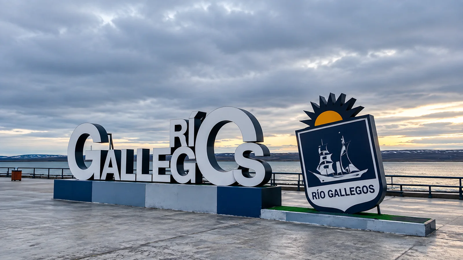 Paseo costero de Río Gallegos con el cartel de la ciudad y el escudo municipal frente al estuario
